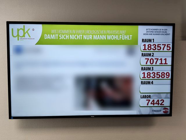 Display im Wartezimmer der UPK Praxisklinik Essen zeigt die aufgerufenen Patientennummern pro Behandlungsraum